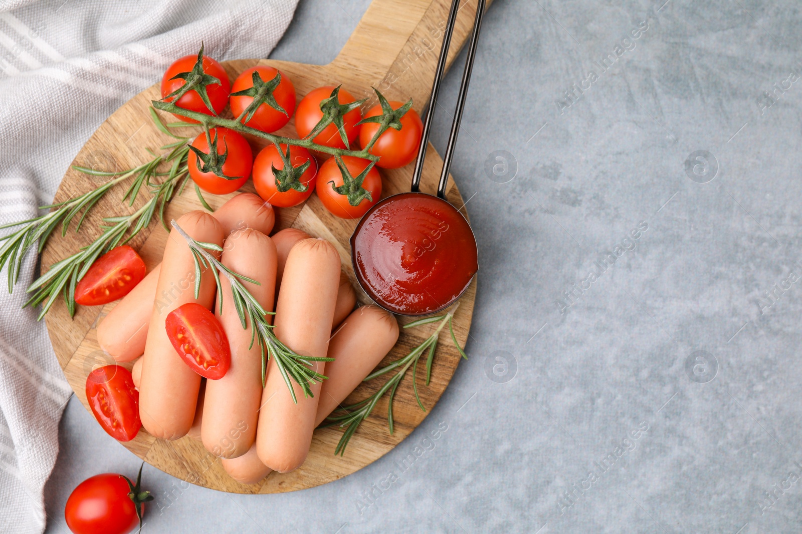 Photo of Delicious boiled sausages, tomato sauce, tomatoes and rosemary on gray table, top view. Space for text