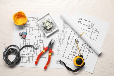 Photo of Wiring diagrams, pliers and different electrician's equipment on white wooden table, flat lay