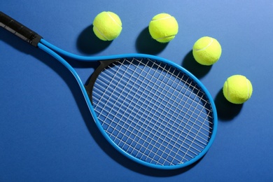 Photo of Tennis racket and balls on blue background, flat lay. Sports equipment