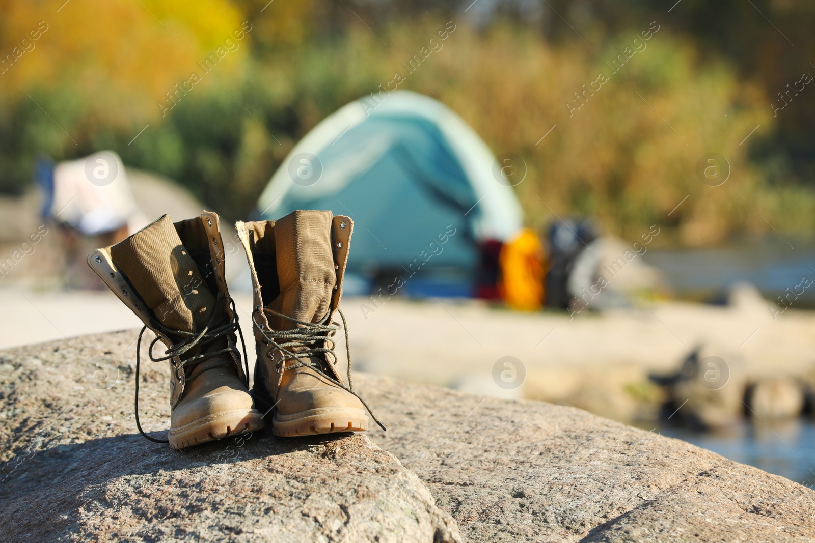 Photo of Boots on rock against blurred background. Space for text