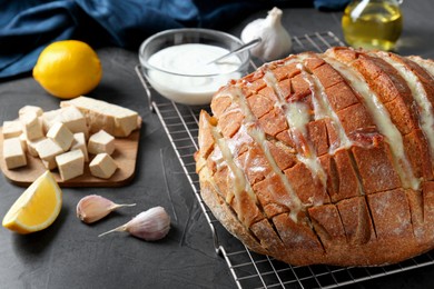 Freshly baked bread with tofu cheese and ingredients on black table, closeup