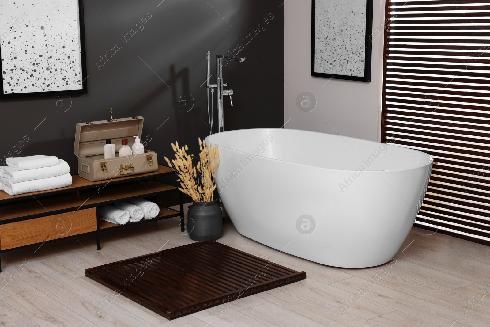 Photo of Stylish bathroom interior with ceramic tub, towels and cosmetic products