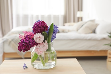 Photo of Beautiful hyacinths in glass vase on table indoors, space for text. Spring flowers