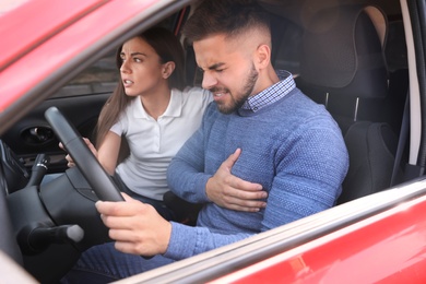 Photo of Young woman and man suffering from heart attack in car