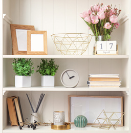 Photo of White shelving unit with plants and different decorative stuff