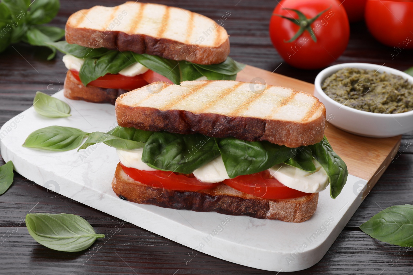 Photo of Delicious Caprese sandwiches with mozzarella, tomatoes and basil on wooden table