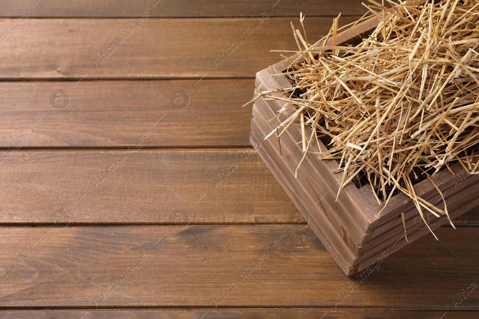 Photo of Dried straw in crate on wooden table, space for text