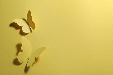 Photo of Paper butterflies on yellow background, top view. Space for text