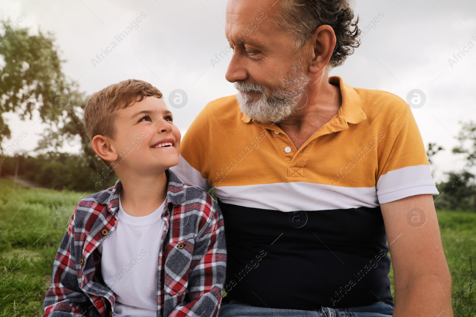 Photo of Cute little boy and grandfather spending time together in park