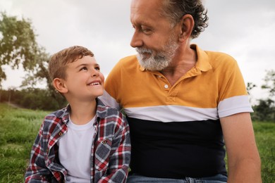 Photo of Cute little boy and grandfather spending time together in park