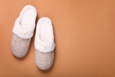 Photo of Pair of beautiful soft slippers on light brown background, top view. Space for text