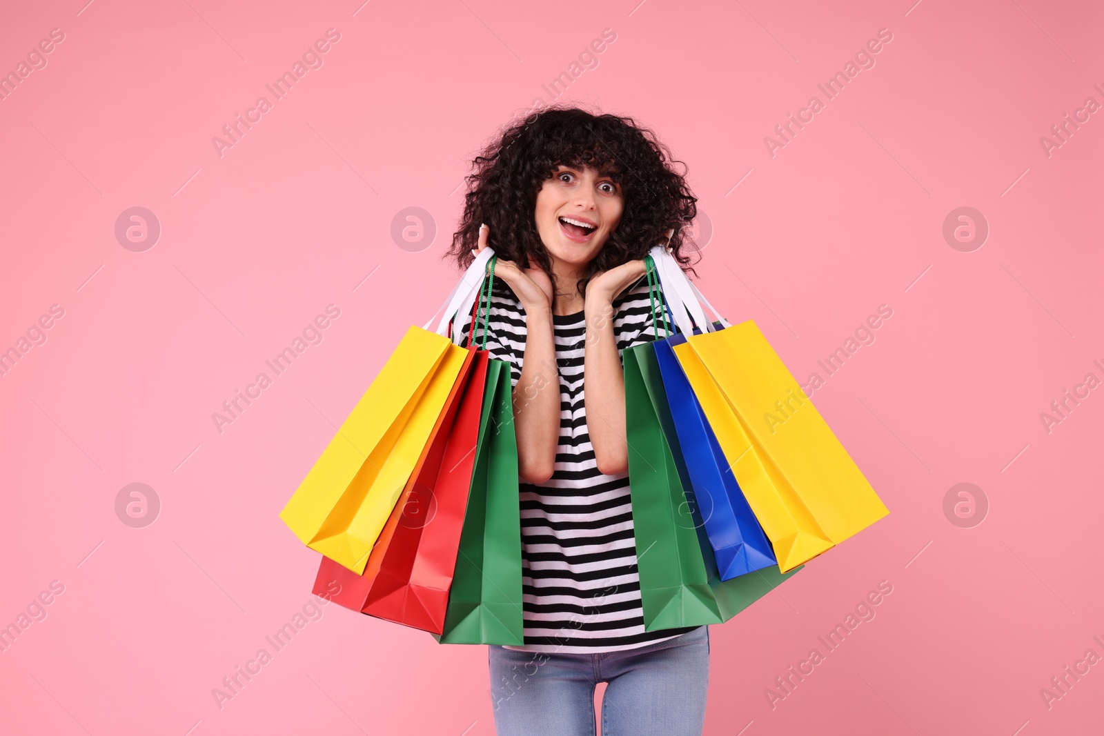 Photo of Happy young woman with shopping bags on pink background