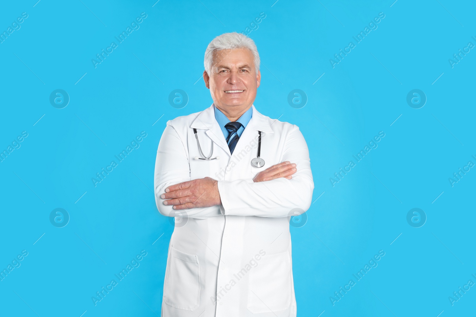 Photo of Senior doctor with stethoscope on light blue background