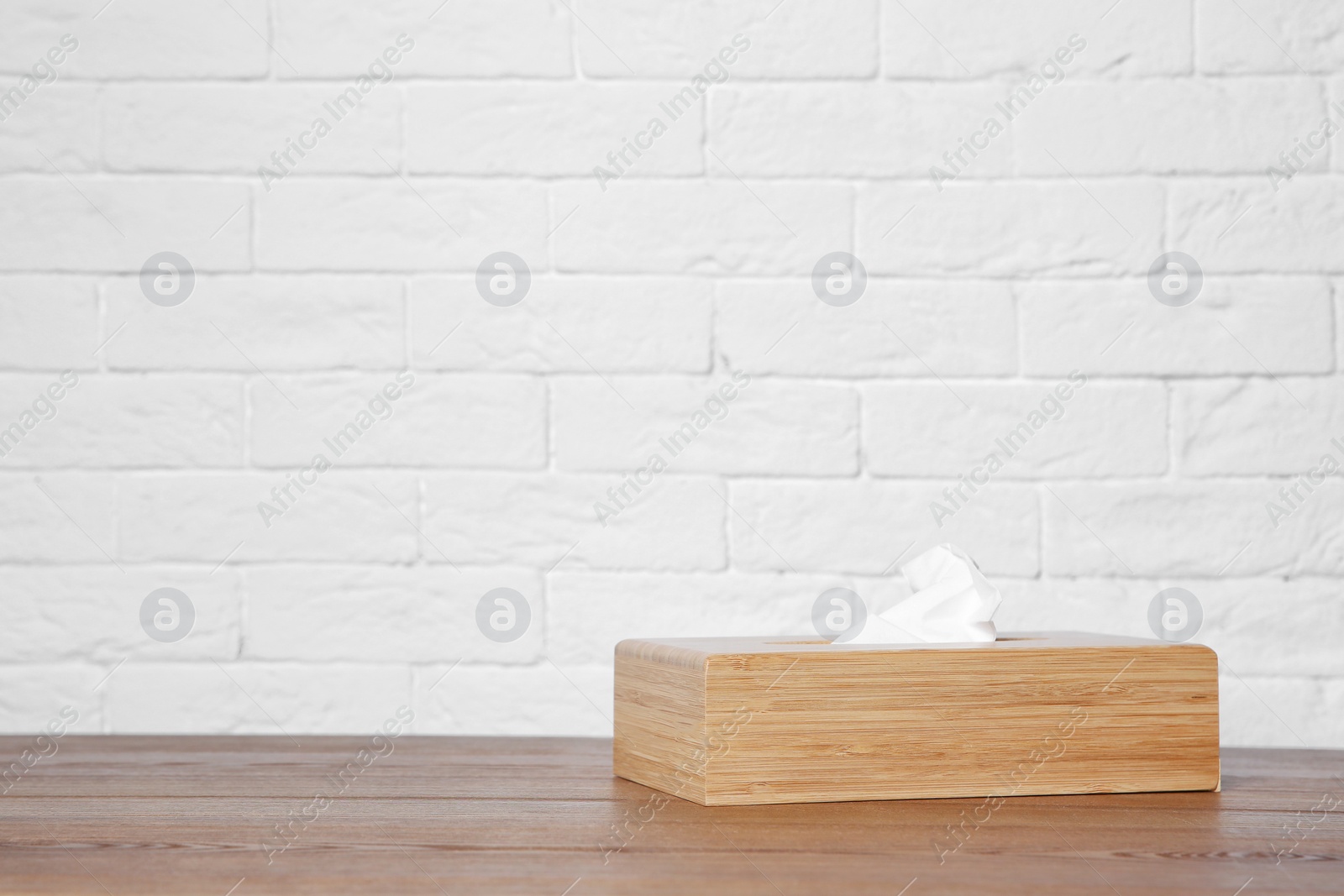 Photo of Napkin holder with paper serviettes on table against brick wall. Space for text