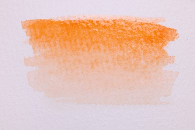 Photo of Abstract orange watercolor painting on white paper, top view