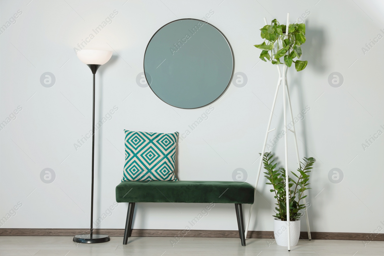 Photo of Stylish round mirror on white wall over bench in room
