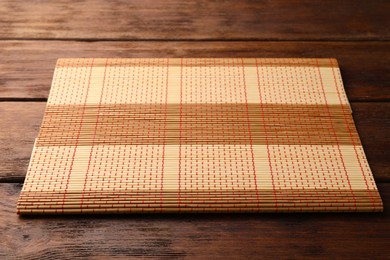 Photo of New bamboo mat on wooden table, space for text