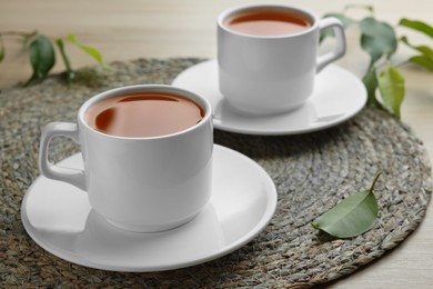Photo of Green tea in white cups with leaves on table, closeup
