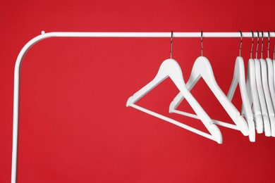 Photo of White clothes hangers on metal rack against red background