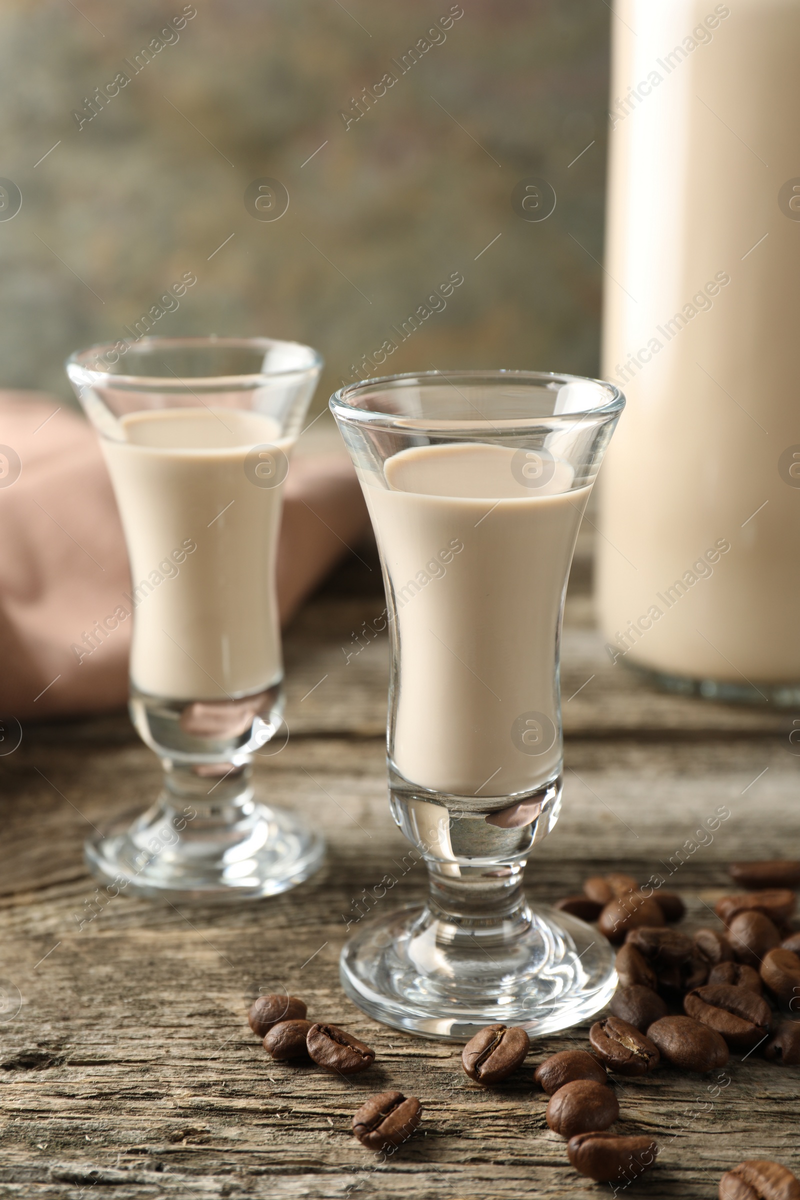 Photo of Coffee cream liqueur in glasses and beans on wooden table