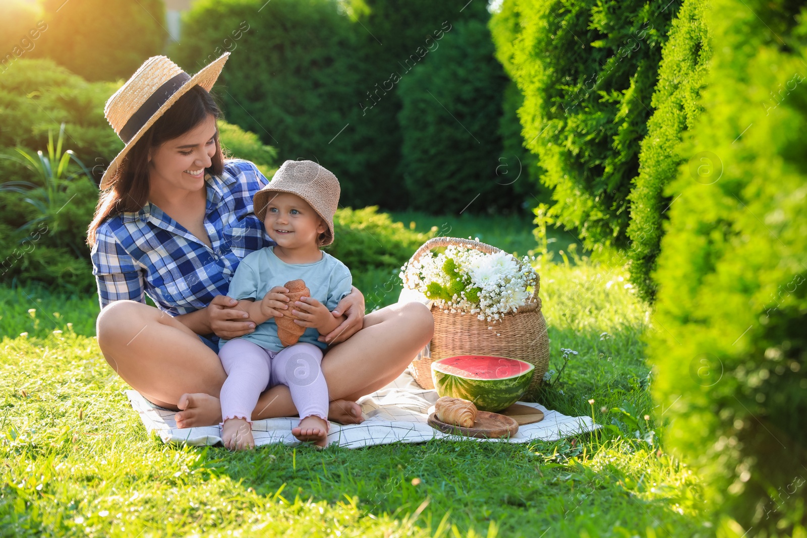 Photo of Mother with her baby daughter having picnic in garden on sunny day