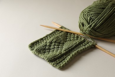 Knitting, soft yarn and needles on beige background