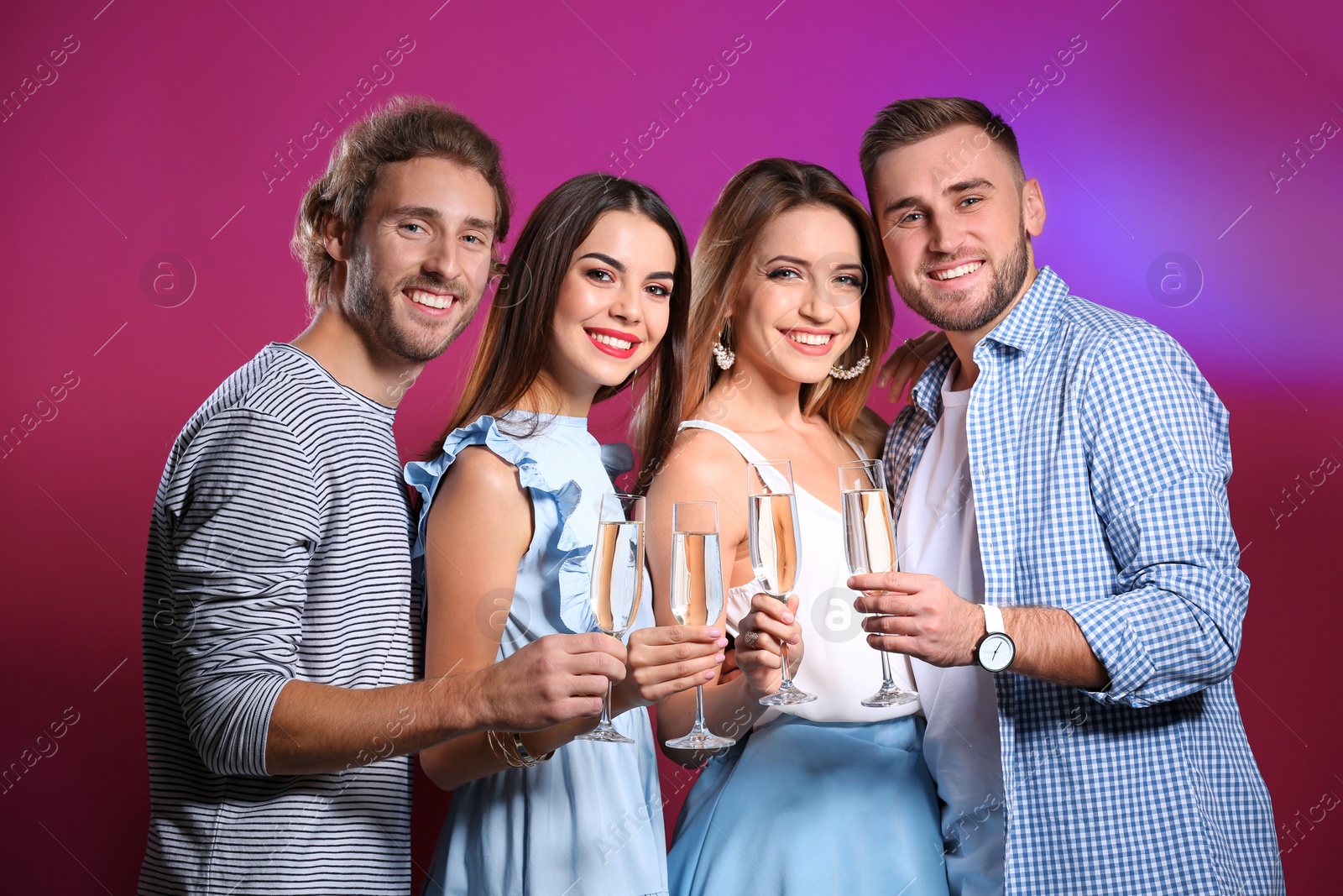 Photo of Portrait of happy friends with champagne in glasses on color background