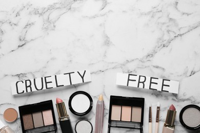 Photo of Flat lay of cards with phrase Cruelty Free and decorative cosmetics on white marble table, space for text. Stop animal tests