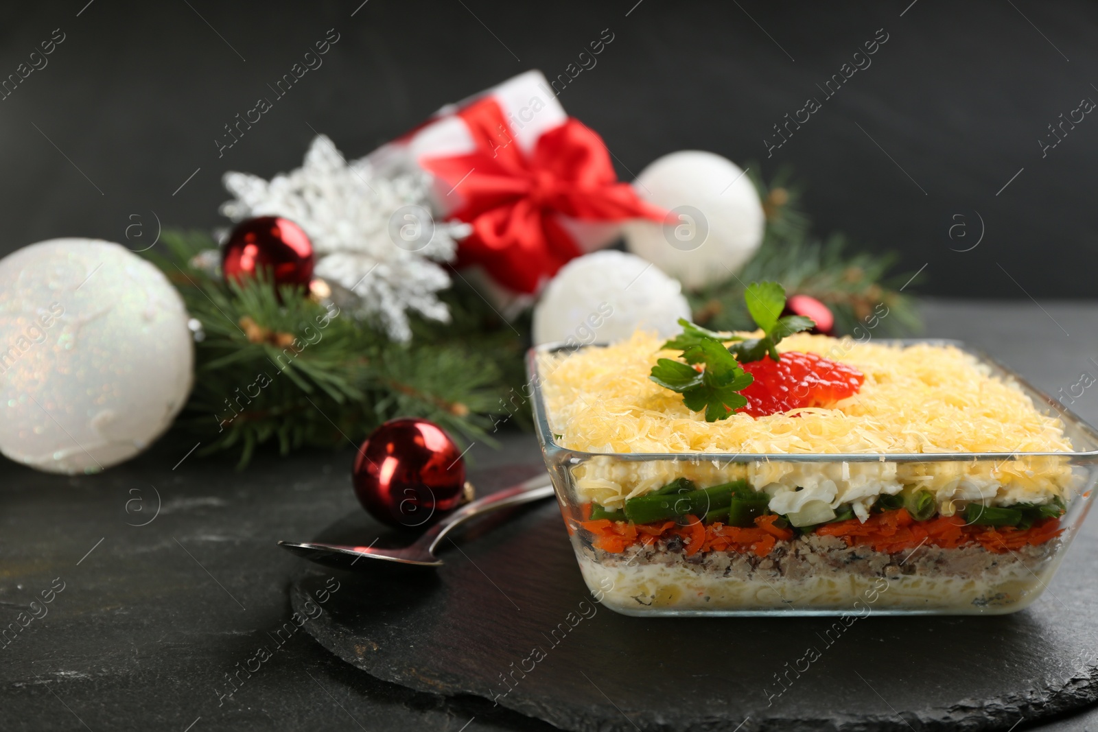 Photo of Traditional russian salad Mimosa and festive decor on black table
