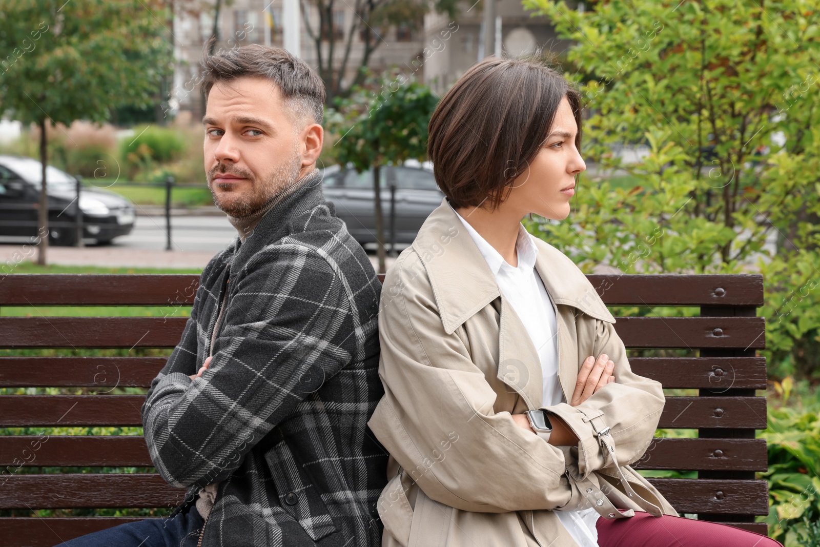 Photo of Unhappy couple sitting on bench outdoors. Relationship problems