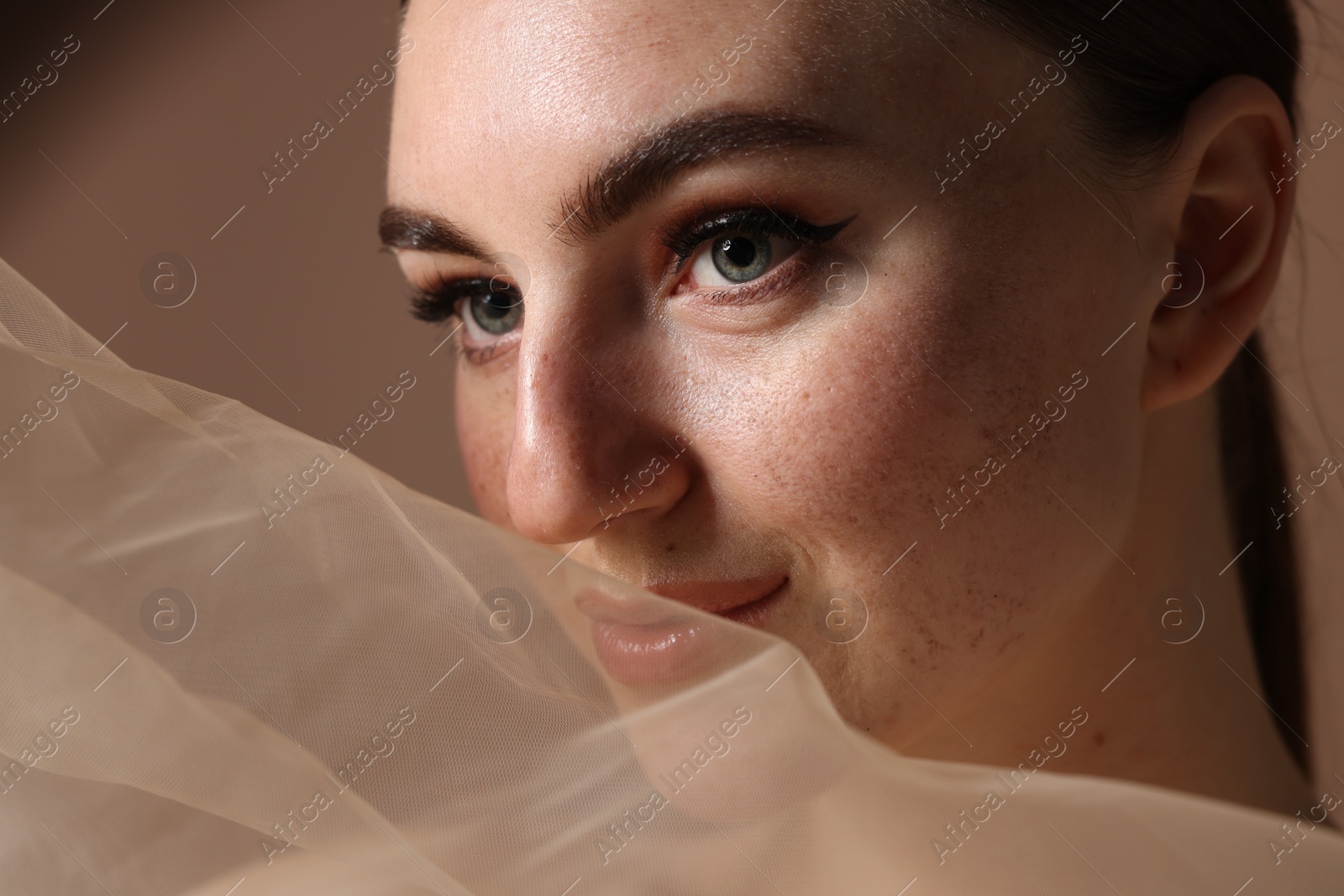 Photo of Fashionable portrait of beautiful woman with fake freckles on brown background, closeup