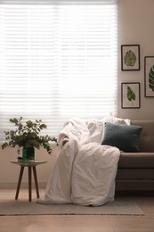 Photo of Comfortable sofa with blanket in stylish room interior