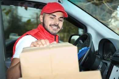 Photo of Young courier checking amount of parcels in delivery van