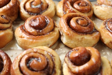 Photo of Tasty cinnamon rolls with cream on parchment paper, closeup