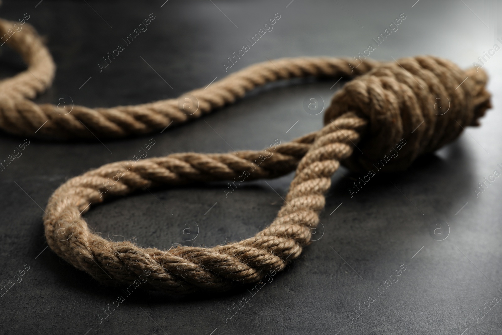 Photo of Rope noose with knot on grey table, closeup