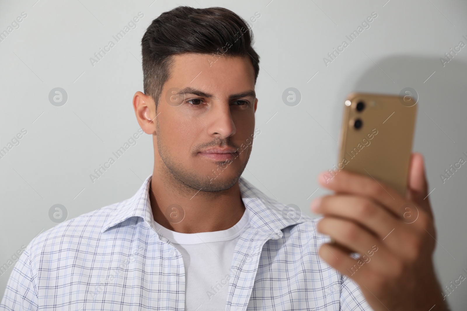 Photo of Man unlocking smartphone with facial scanner on white background. Biometric verification