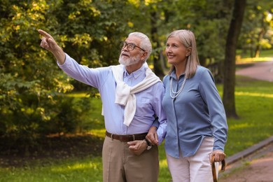 Photo of Senior man with walking cane and mature woman in park