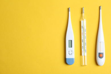 Photo of Different thermometers on yellow background, flat lay. Space for text