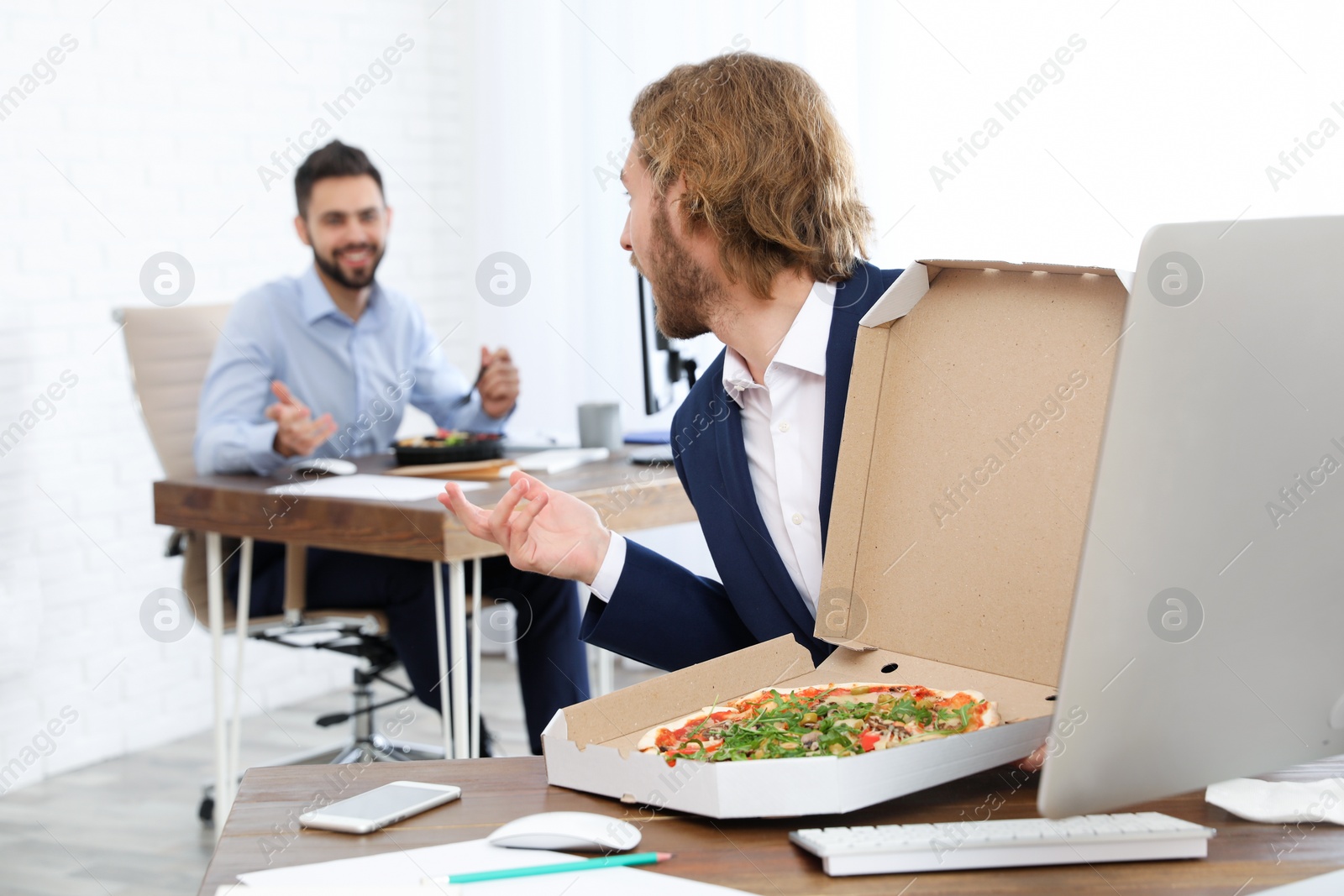 Photo of Office employees having lunch at workplace. Food delivery