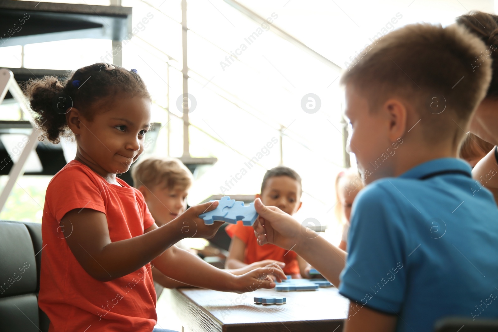 Photo of Little children holding puzzle pieces in hands, indoors. Unity concept