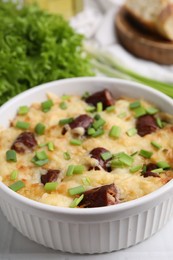 Photo of Tasty sausage casserole with green onion in baking dish on white table, closeup