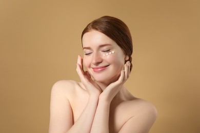 Photo of Beautiful woman with freckles and cream on her face against beige background