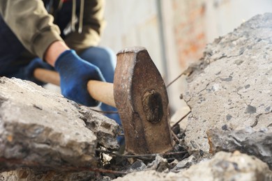 Photo of Man breaking stones with sledgehammer outdoors, closeup