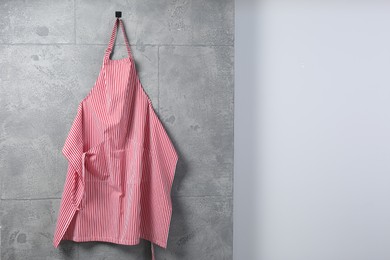 Clean red striped apron on grey tiled wall. Space for text
