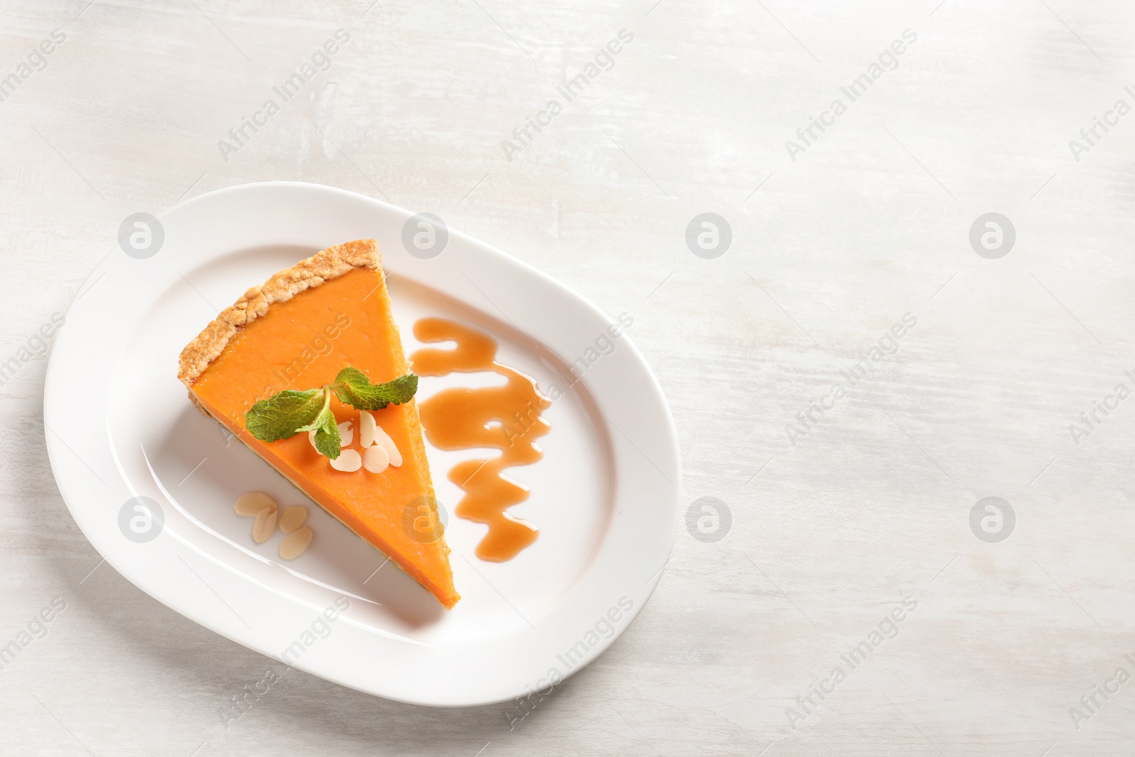 Photo of Plate with piece of fresh delicious homemade pumpkin pie on light background, top view. Space for text