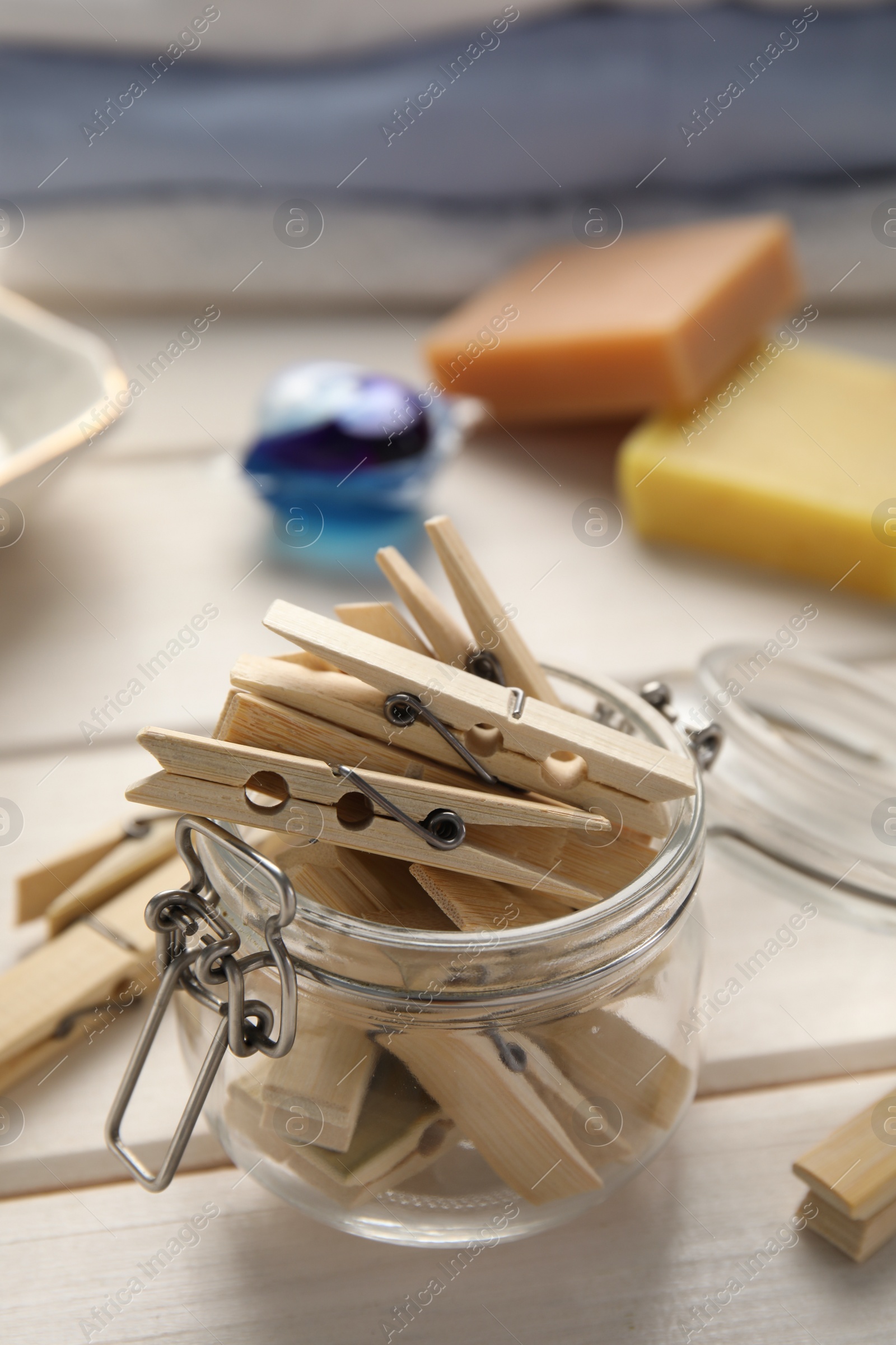 Photo of Many wooden clothespins and glass jar on white table