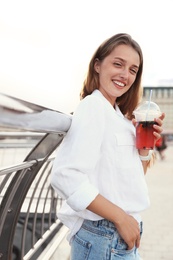 Young woman with refreshing drink on city street