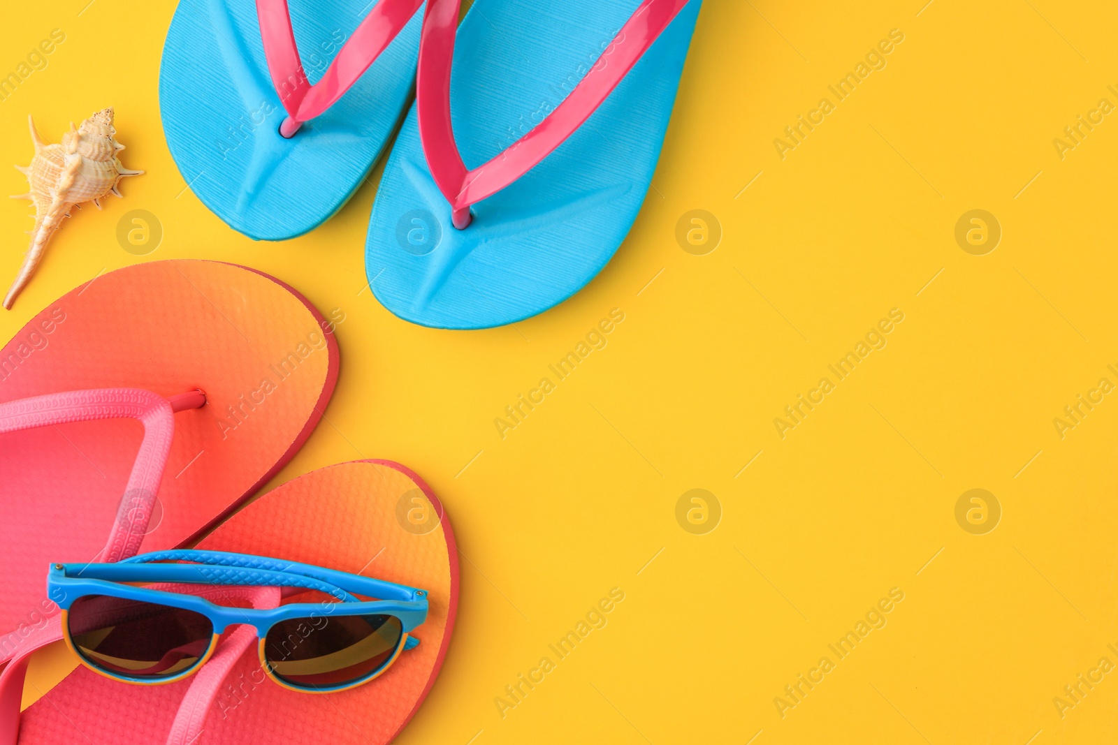 Photo of Flip flops and sunglasses on yellow background, flat lay with space for text. Beach accessories