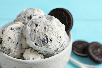 Bowl with ice cream and crumbled chocolate cookies on table, closeup. Space for text