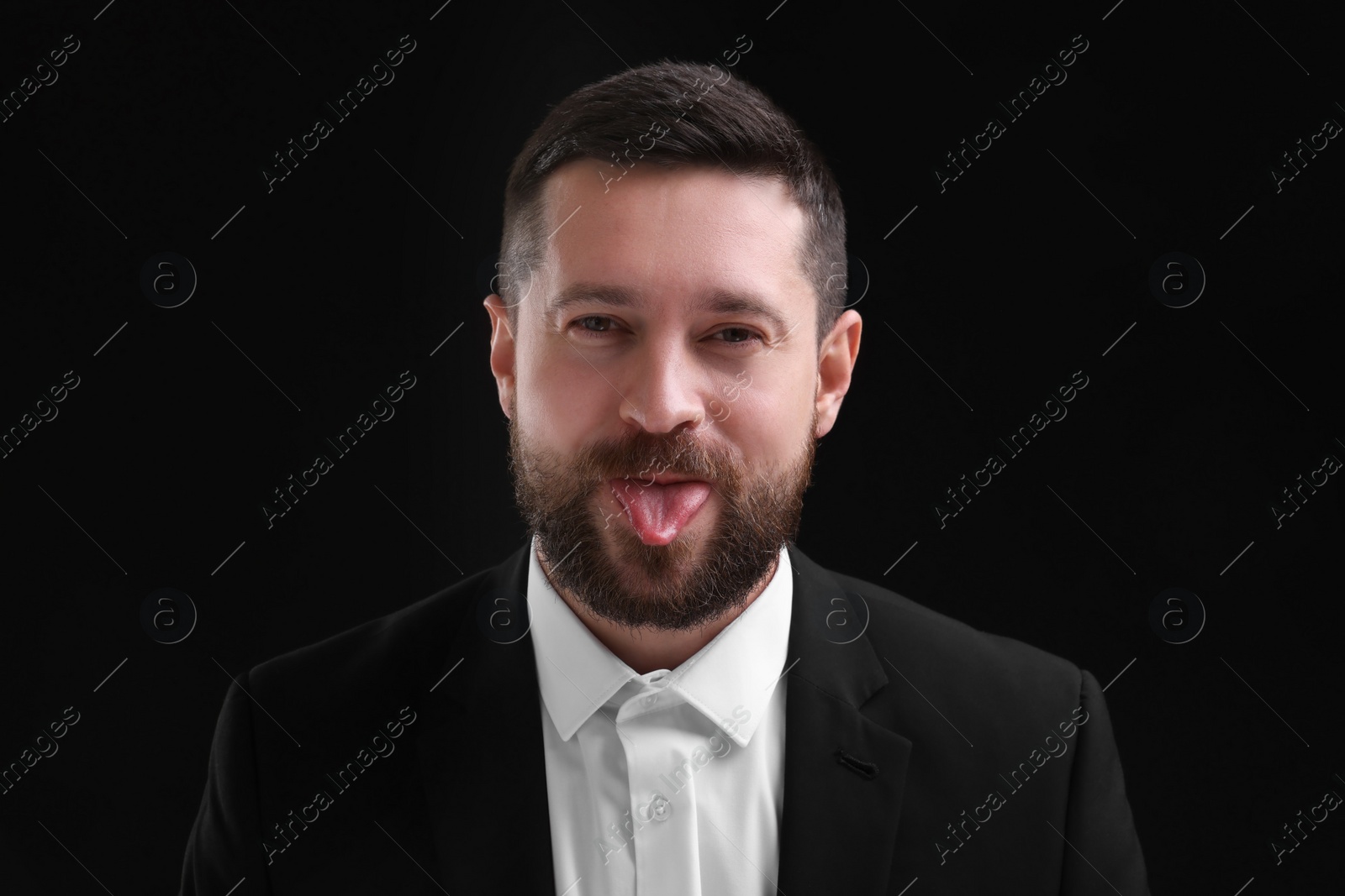 Photo of Personality concept. Handsome man showing tongue on black background